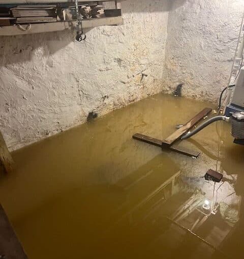 Flooded basement with standing brown water, highlighting potential water damage risks and the need for effective basement waterproofing solutions.