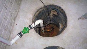 Sump pump installed in a basement sump pit with drainage pipe, illustrating essential flood prevention mechanism for basement waterproofing.