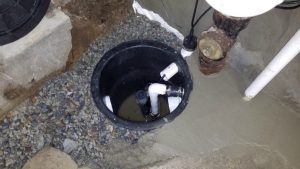 Sump pump installation in a basin with PVC discharge pipe and gravel base, illustrating proper setup for efficient water management in basements.