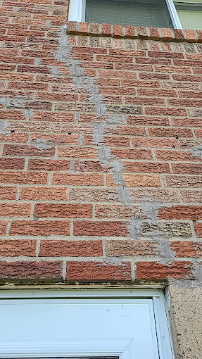 Exterior brick wall with visible foundation crack repair and patched masonry on residential home