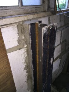 Basement wall repair with carbon fiber strap and wall anchor for structural stabilization.