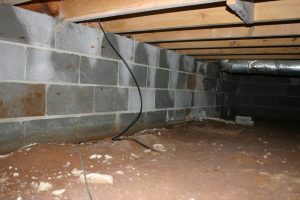 Crawlspace with exposed brick foundation and vapor barrier illustrating moisture problems and encapsulation solutions.