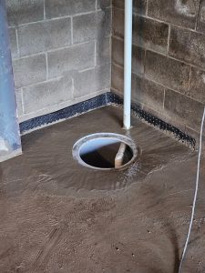 Basement floor with sump pump and drainage system illustrating interior waterproofing solutions.