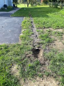 Excavated trench around foundation showing invasive exterior waterproofing challenges and loose soil.